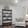 a room with a white chair and a book shelf with art on it